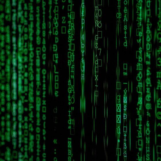 Green matrix-style streams of letters and symbols cascading down a dark background, representing computer code.