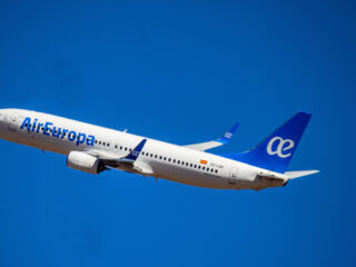 Air Europa passenger jet in mid-flight against a clear blue sky, tail fin visible with logo