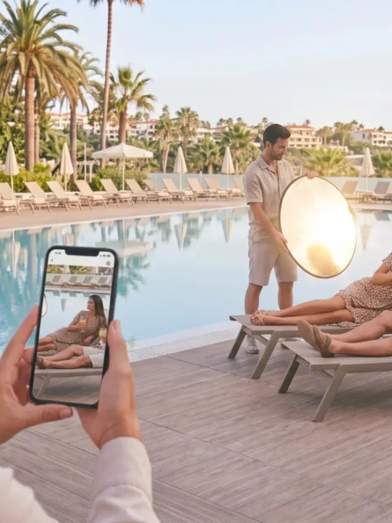 Photographer captures a couple lounging by a pool while using a reflective round light nearby, with a guest taking a photo in the foreground.