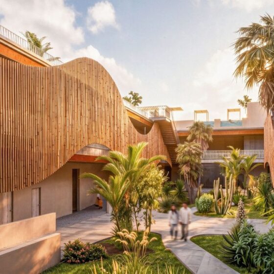 Curved wooden-clad courtyard with tropical plants and a central walkway; blurred people stroll along the path.