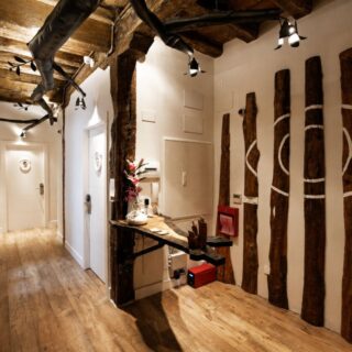 Rustic hallway with exposed wooden beams, log pillars, and a reception counter on the right.