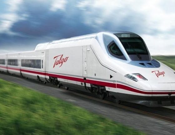 White Talgo high-speed train with red stripe racing along a rural railway on a sunny day.