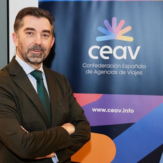 Professional man in a suit with arms crossed standing beside a CEAV banner.