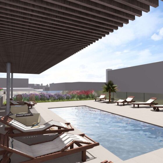 Rooftop pool deck with wooden lounge chairs, a shaded pergola, and planters against a city skyline backdrop.