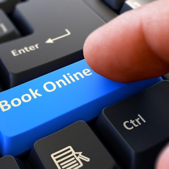 Finger pressing a blue 'Book Online' key on a keyboard near the Enter and Ctrl keys.