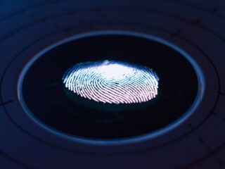 Close-up of a blue-lit fingerprint on a circular biometric scanner surface