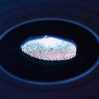 Close-up of a blue-lit fingerprint on a circular biometric scanner surface