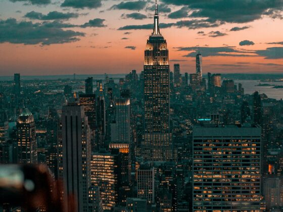 New York City skyline at dusk with the Empire State Building lit up against a pink and teal sky.