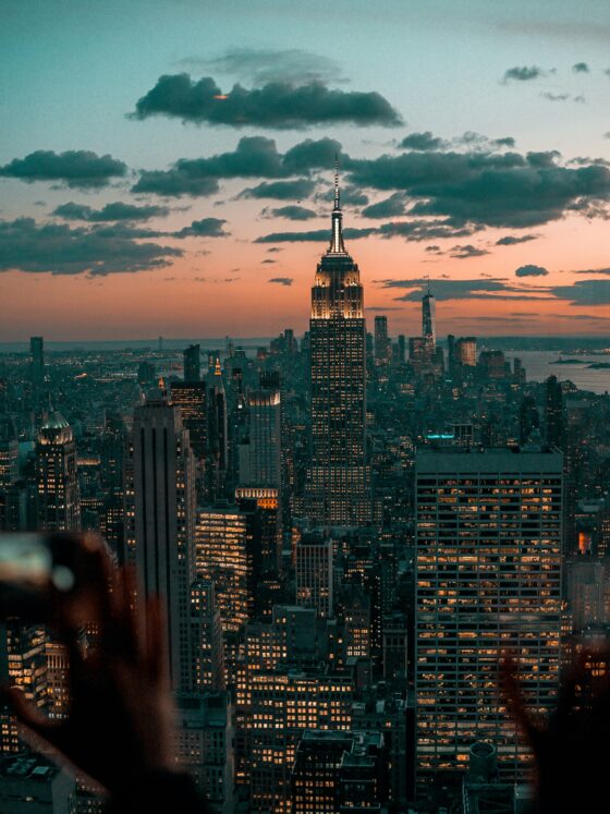 New York City skyline at dusk with the Empire State Building lit up against a pink and teal sky.