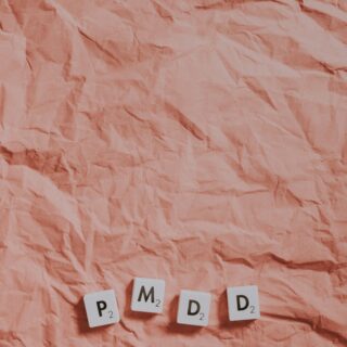 Wrinkled pink paper background with four Scrabble-style tiles at the bottom reading 'P₂', 'M₂', 'D₂', 'D₂' arranged in a gentle arc.