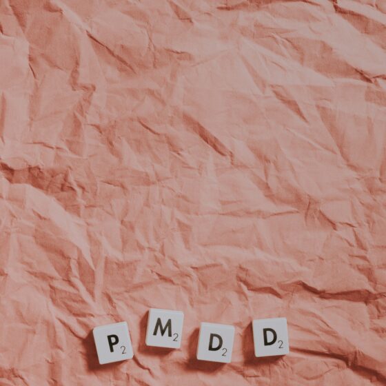Wrinkled pink paper background with four Scrabble-style tiles at the bottom reading 'P₂', 'M₂', 'D₂', 'D₂' arranged in a gentle arc.