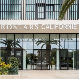 Eurostars California hotel entrance with glass doors and palm trees in front.