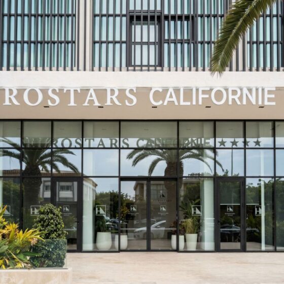 Eurostars California hotel entrance with glass doors and palm trees in front.
