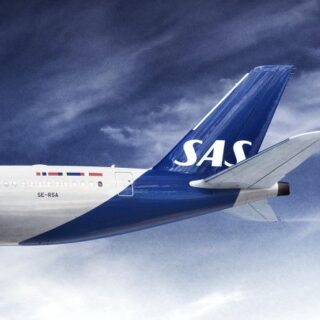 Tail of a SAS commercial jet in blue with white SAS lettering flying against a cloudy blue sky, left fuselage visible.