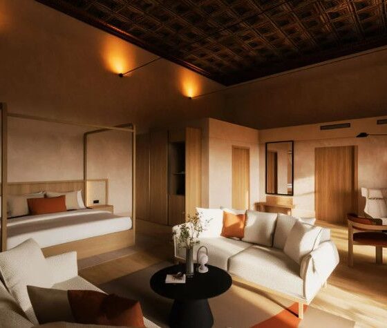 Luxurious hotel suite with a canopy bed, white and orange accents, and a living area under warm lighting.