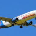 Jet2holidays passenger airplane in clear blue sky, mid-flight, with landing gear retracted and branding visible on fuselage.