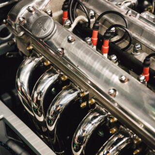 Close-up of a polished car engine with chrome valve covers, red ignition wires, and bolts.