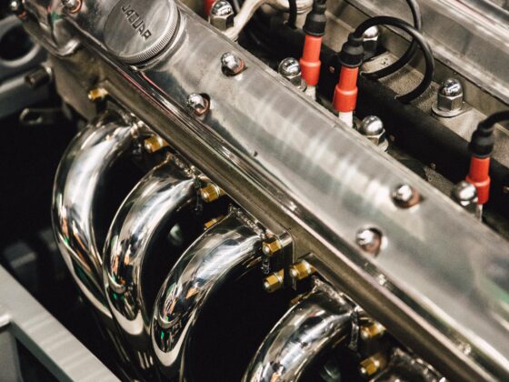 Close-up of a polished car engine with chrome valve covers, red ignition wires, and bolts.