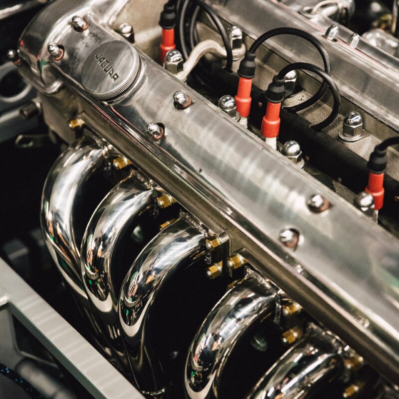 Close-up of a polished car engine with chrome valve covers, red ignition wires, and bolts.